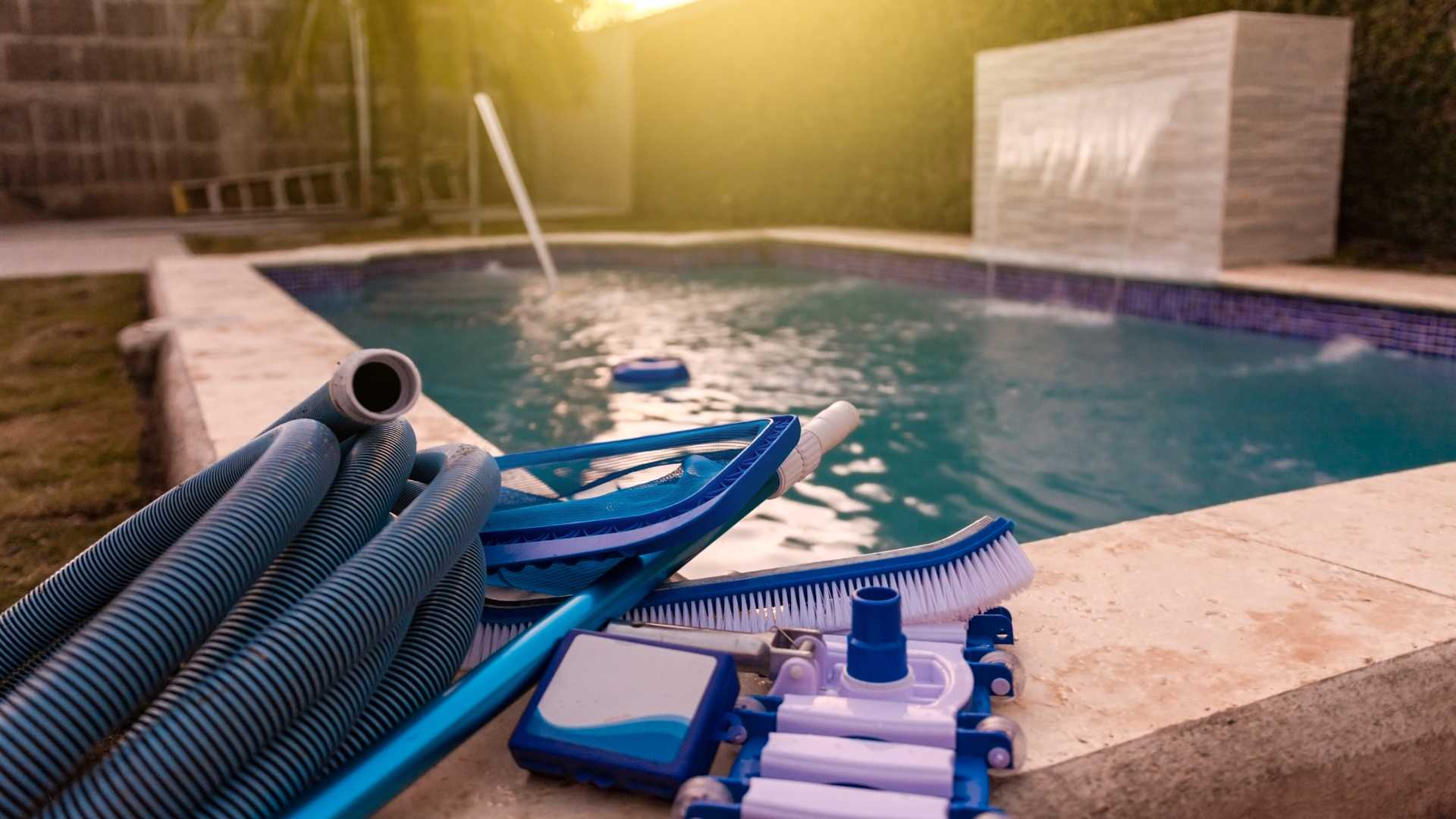 Pool cleaning tools next to pool at sunset. Comprehensive winterization.