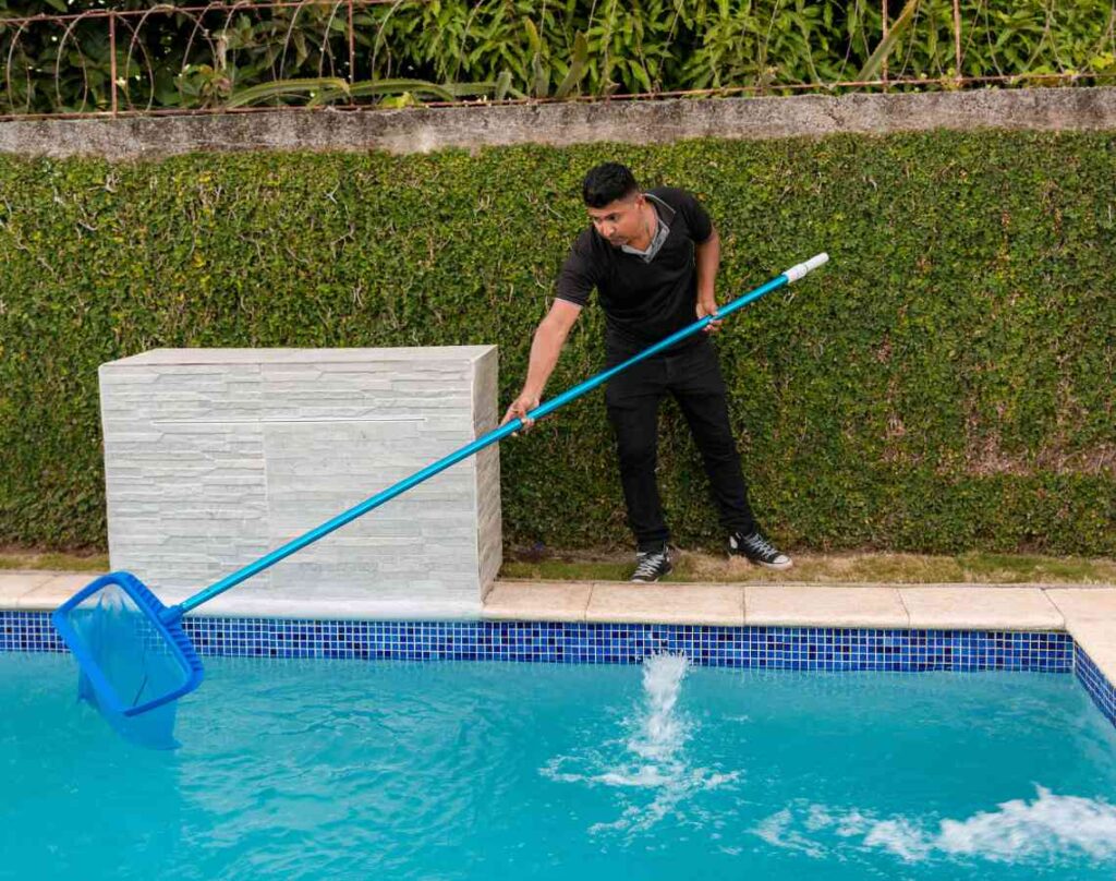 Person cleaning pool with net. Maintaining a healthy pool environment.