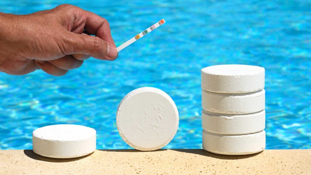 Hand holding pH indicator next to pool. Top pool treatment products.