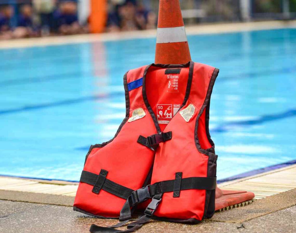 Life jacket in front of orange cone next to pool. The hidden dangers in your pool.