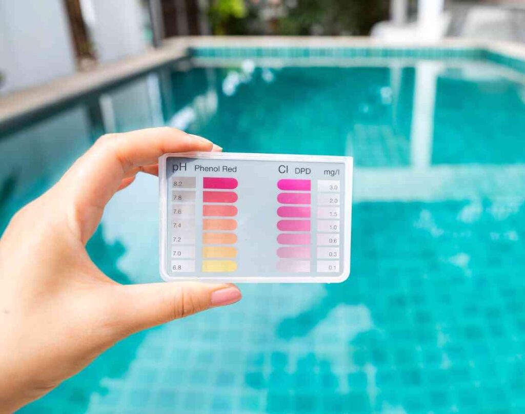 pH tester with pool in the background. Preparing your pool for the swim season.